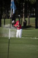 golfer hitting a sand bunker shot photo