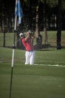 golfer hitting a sand bunker shot photo