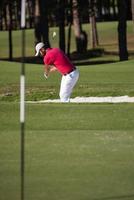 golfer hitting a sand bunker shot photo