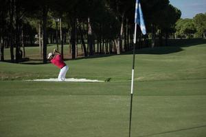 golfer hitting a sand bunker shot photo