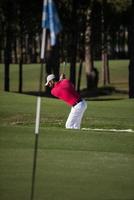 golfista golpeando un tiro de búnker de arena foto