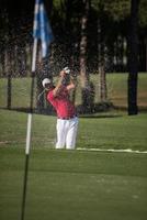 golfista golpeando un tiro de búnker de arena foto