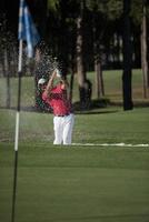 golfer hitting a sand bunker shot photo