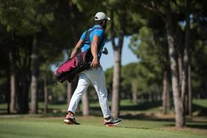 golf player walking and carrying bag photo