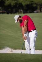 golfista golpeando un tiro de búnker de arena foto