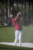 golfer hitting a sand bunker shot photo