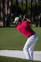 golfista golpeando un tiro de búnker de arena foto