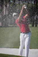 golfer hitting a sand bunker shot photo