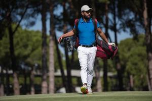 golf player walking and carrying bag photo