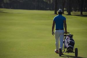 jugador de golf caminando con bolsa de ruedas foto