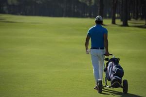 jugador de golf caminando con bolsa de ruedas foto