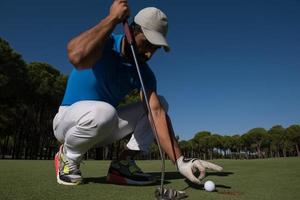 mano del hombre poniendo una pelota de golf en el agujero foto