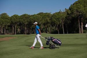 golf player walking with wheel bag photo