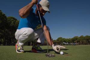 man's hand putting golf ball in hole photo