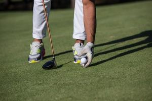 golf player placing ball on tee photo