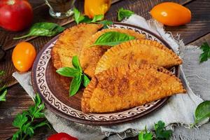 Traditional Crimean Tatar cuisine, chebureki with chicken meat. Fried empanadas on wooden background photo