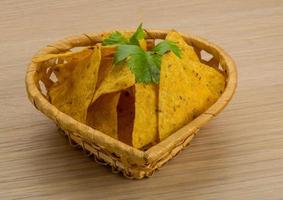 Nachos in a basket on wooden background photo