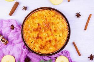 Delicious homemade apple pie on pink background. Apple pie with ingredients, apples and cinnamon. Top view photo