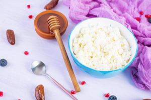 requesón con miel y bayas sobre fondo rosa. desayuno vegetariano ligero foto