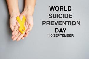 día mundial de prevención del suicidio, mano con cinta amarilla para apoyar a las personas que viven y están enfermas