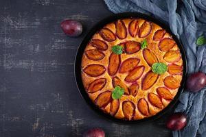 Delicious plum cake on wooden background. Homemade plum pie. Top view photo