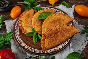 Traditional Crimean Tatar cuisine, chebureki with chicken meat. Fried empanadas on wooden background photo