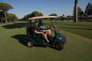 golf players driving cart at course photo