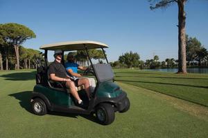 golf players driving cart at course photo