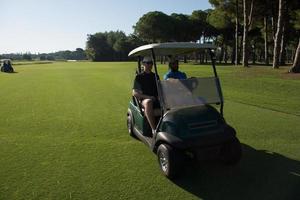 jugadores de golf conduciendo un carro en el campo foto