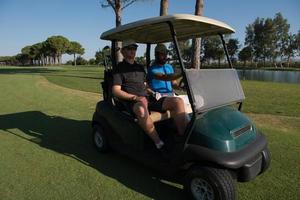 jugadores de golf conduciendo un carro en el campo foto