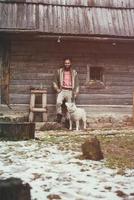 hipster con perro frente a casa de madera foto