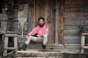 portrait of young hipster in front of wooden house photo