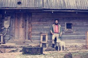 hipster con perro frente a casa de madera foto