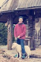 young hipster with dog in front of wooden house photo