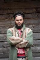 portrait of young hipster in front of wooden house photo