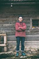 young hipster in front of wooden house photo