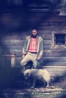 hipster with dog in front of wooden house photo