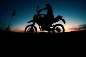 siluetas masculinas y motos de motocross. parque para relajarse en las montañas por la noche. concepto de ocio y viajes de aventura foto