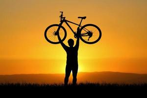 Man holds a bicycle on top of a mountain. concept of success and victory photo