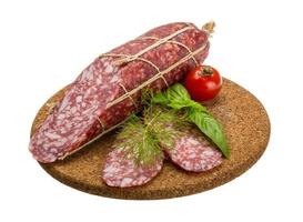 Salami on wooden plate and white background photo
