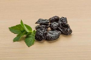 Dry plums on wooden background photo