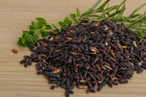 Wild black and brown rice on wooden background photo
