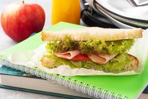 Snack for school with sandwich, fresh Apple and orange juice. Colorful school supplies, photo