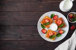 Cottage cheese casserole with strawberries and mint. Delicious homemade dessert made of curd and fresh berries with cream. dark wooden background, copy space. photo