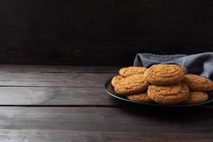 Natural homemade oatmeal cookies on a plate, dark wooden background, copy space. photo