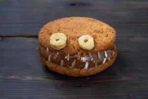 Cookies with cream paste in the shape of monsters for Halloween celebration. Funny homemade faces made of oatmeal cookies and boiled condensed milk. copy space photo