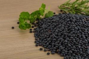 Raw black lentils on wooden background photo