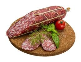 Salami on wooden plate and white background photo