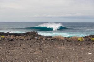 Turbulent ocean waves with white foam beat coastal stones photo