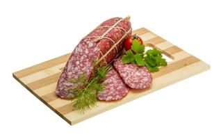 Salami on wooden plate and white background photo